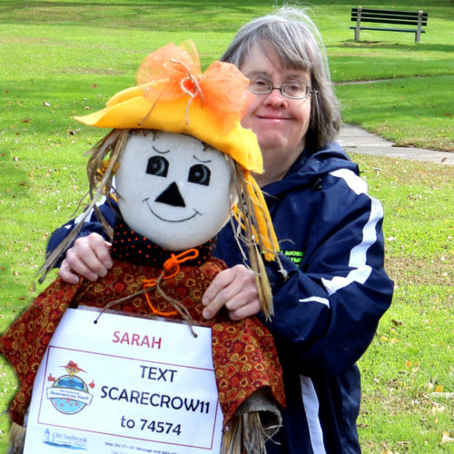Woman from SARAH Inc. Enrichment Services on the Westbrook Green with a scarecrow