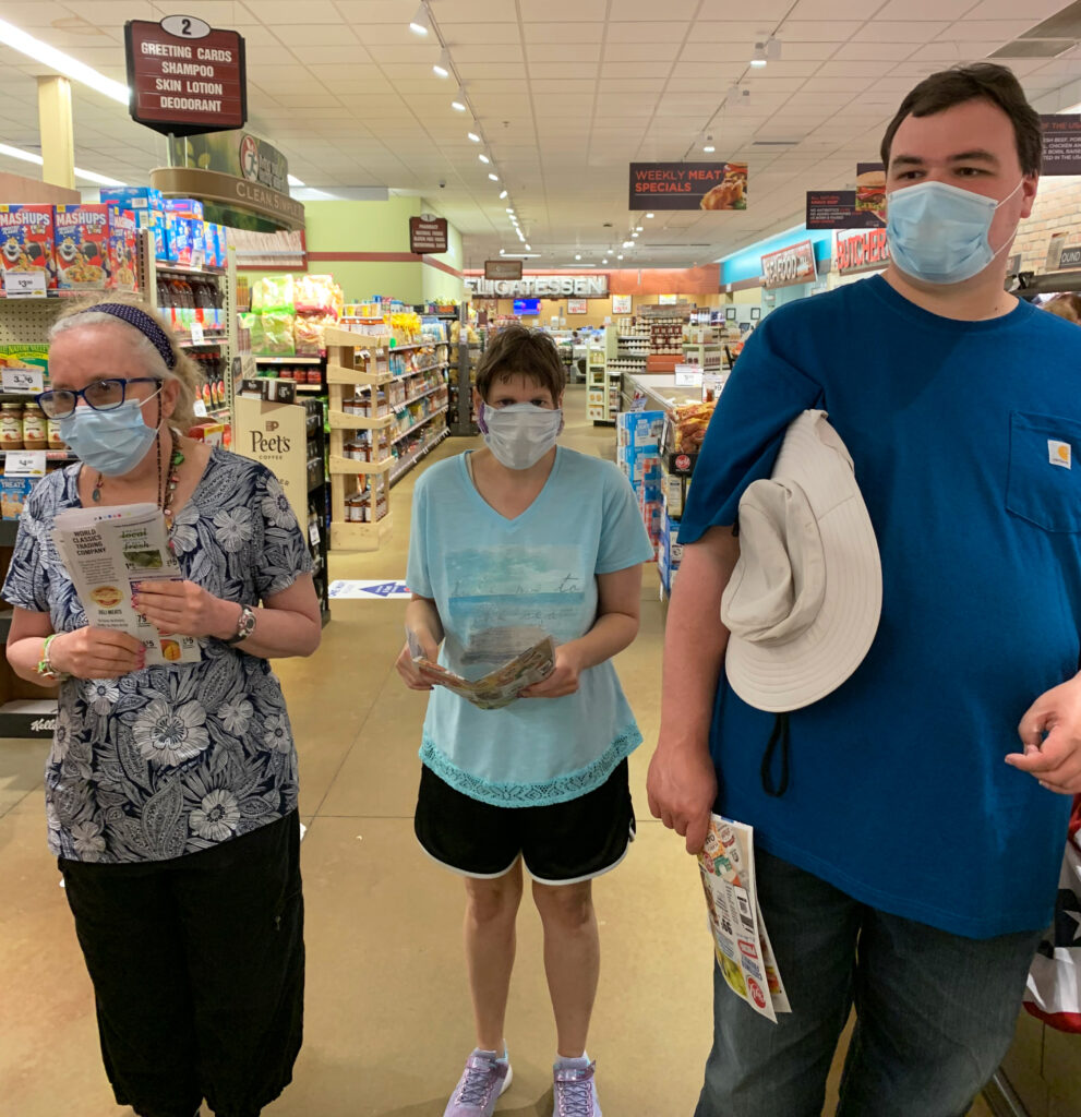 A group stands in a grocery store with flyers in their hands