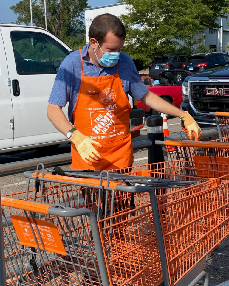 A man working at Home Depot organizes carts in a cart return in the parking lot